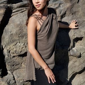 Woman modeling LYC Moab Top in Desert Crepe Mezcal, and leaning on rocks.